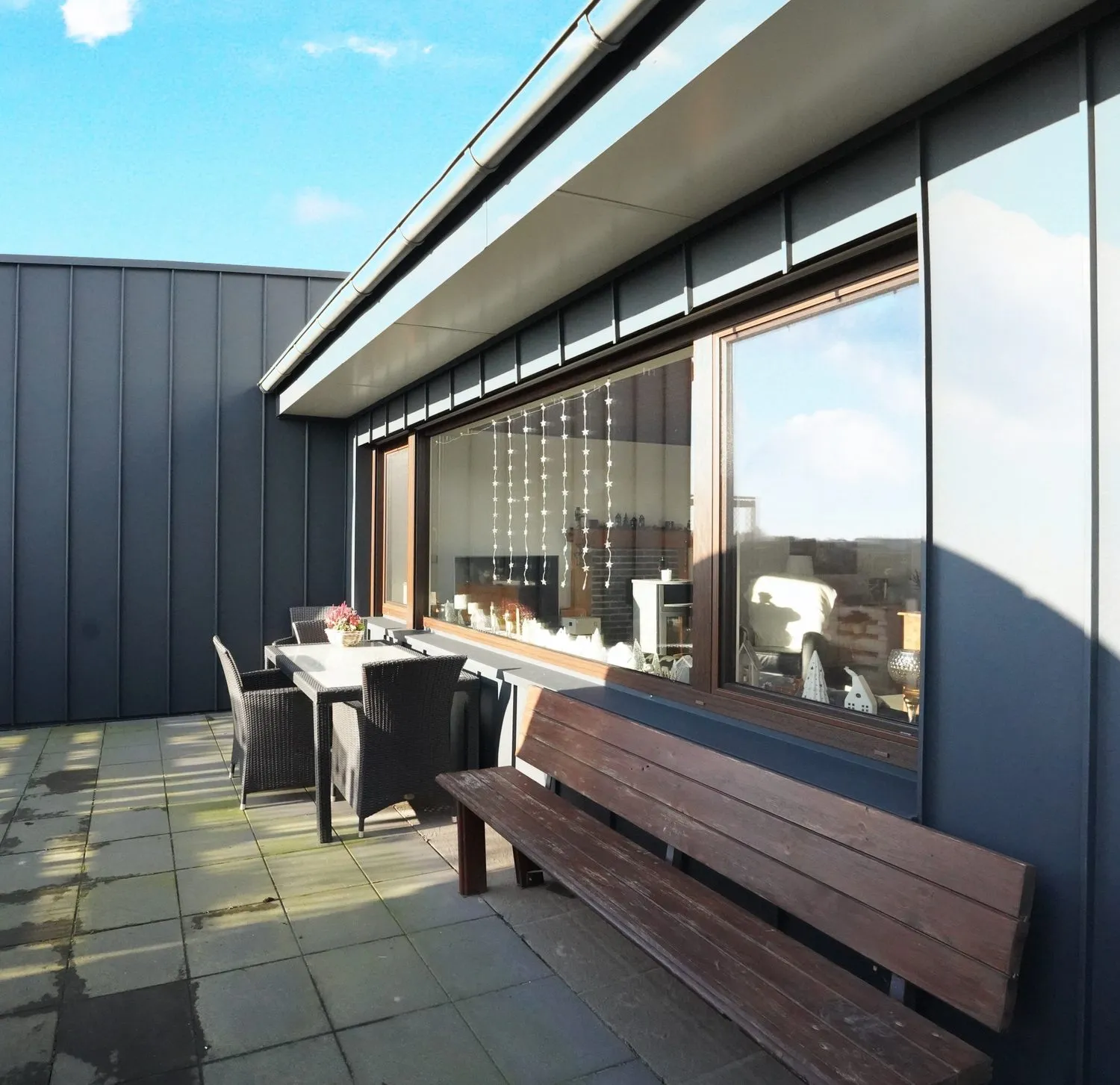 Dachterrasse mit anthrazitfarbener Metallfassade und Sitzbank