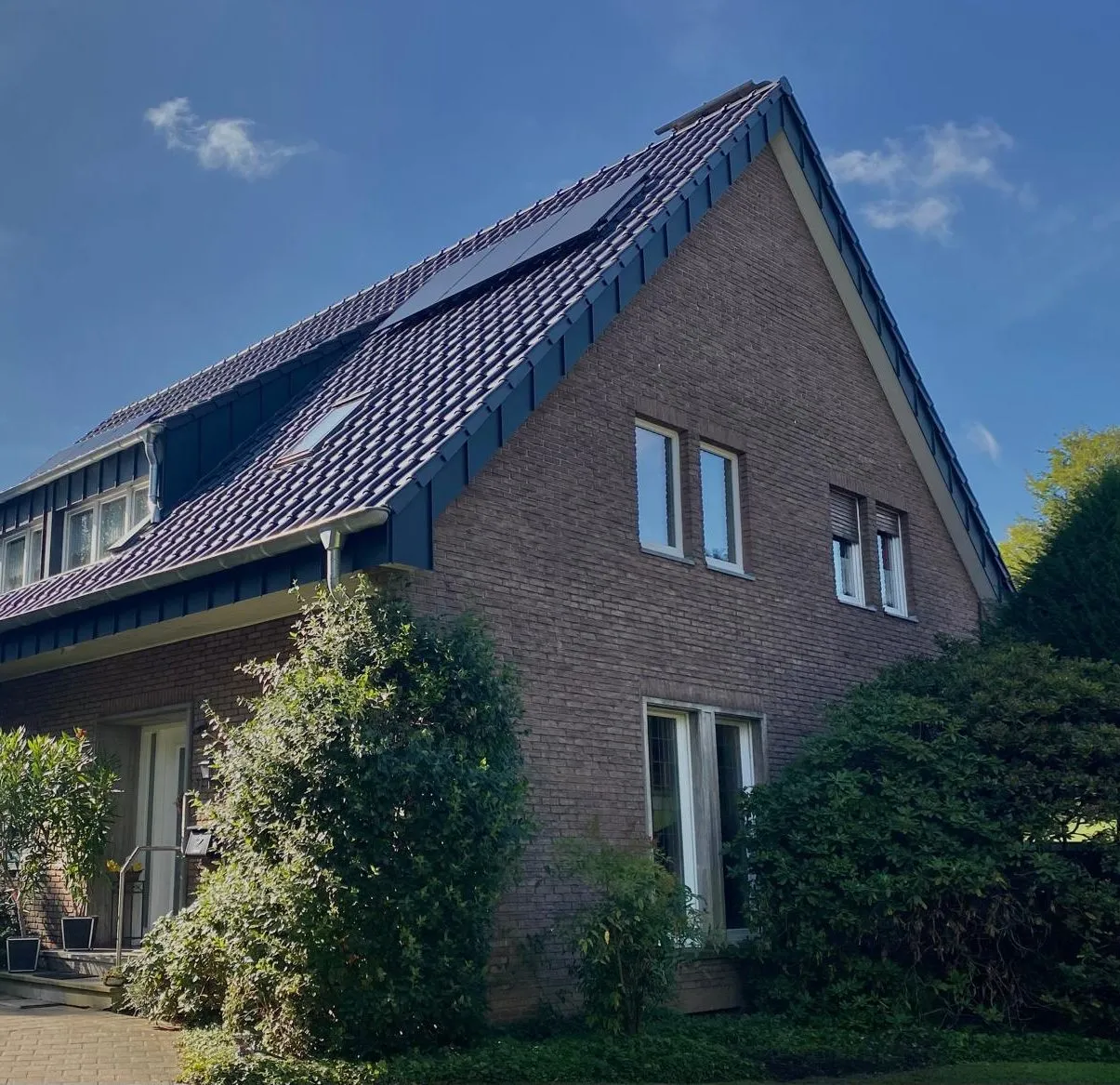 Backsteinhaus mit dunklem Ziegeldach und Gauben