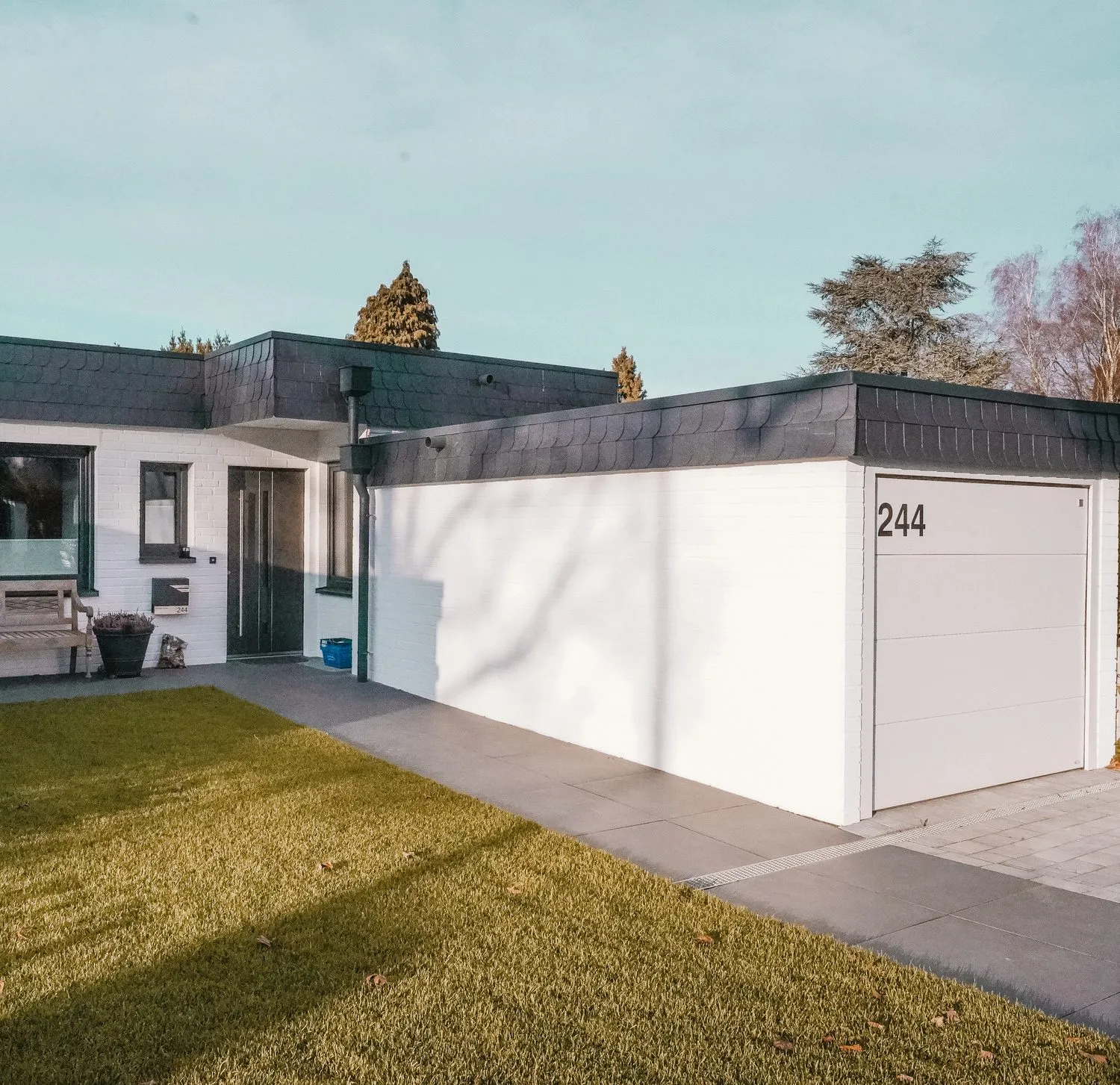 Bungalow mit Flachdach und weißer Garage