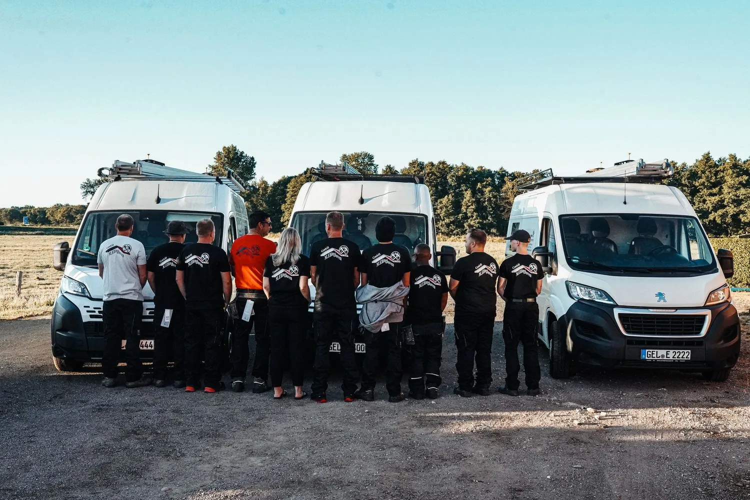 Das Team steht in einer Reihe vor drei Transportern